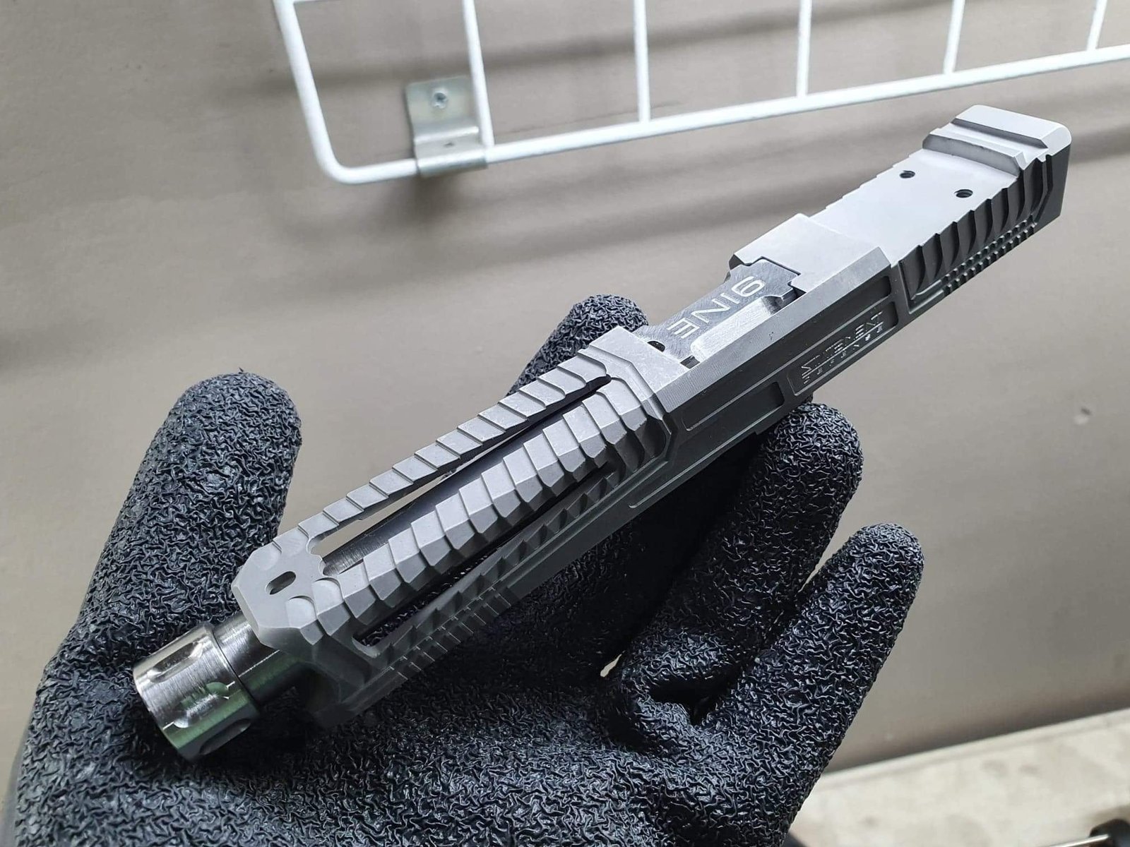 Precision-machined silver and black sporting pistol slide held during inspection